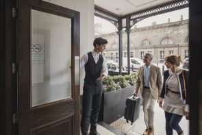 concierge opening hotel door for guests