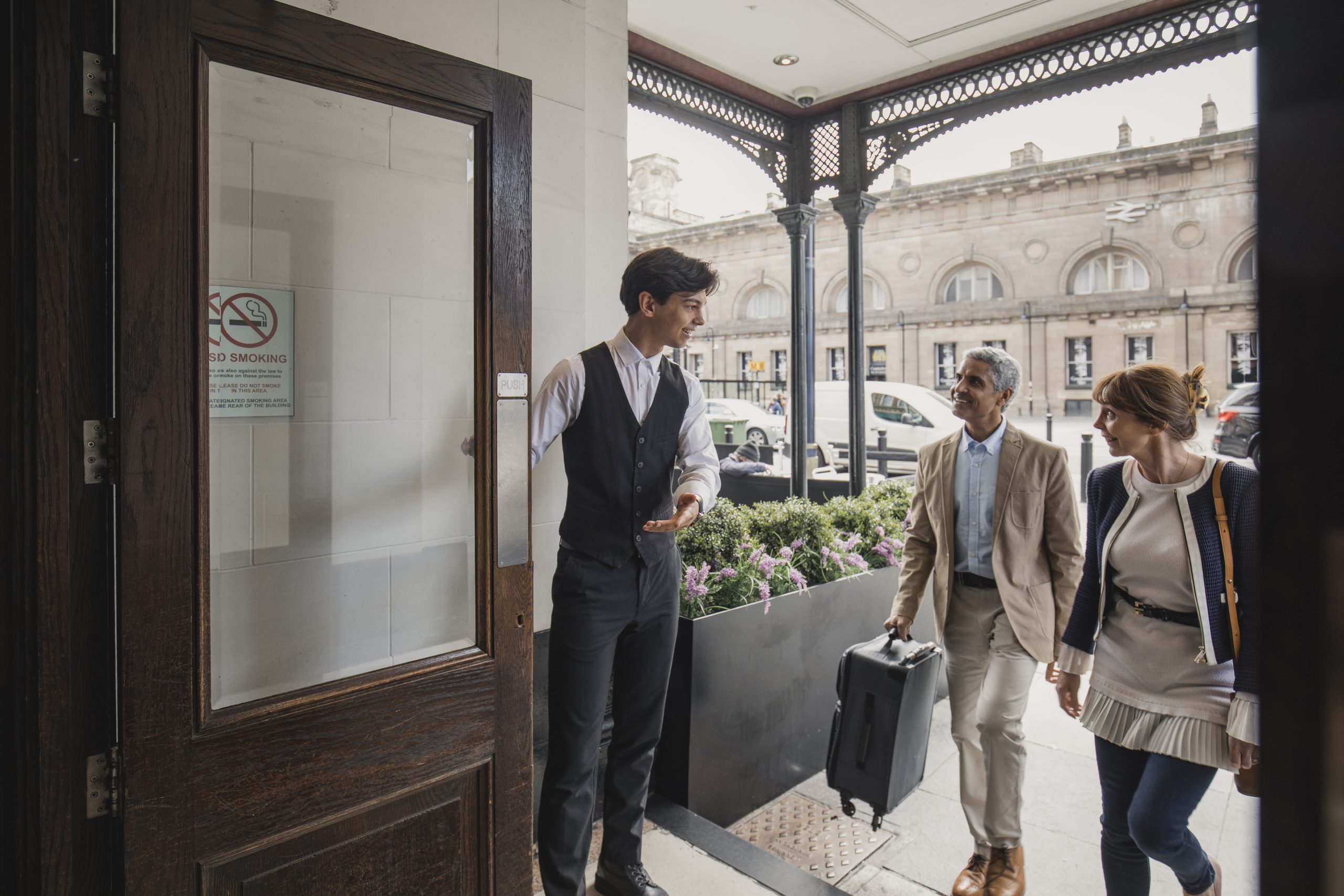 concierge opening hotel door for guests